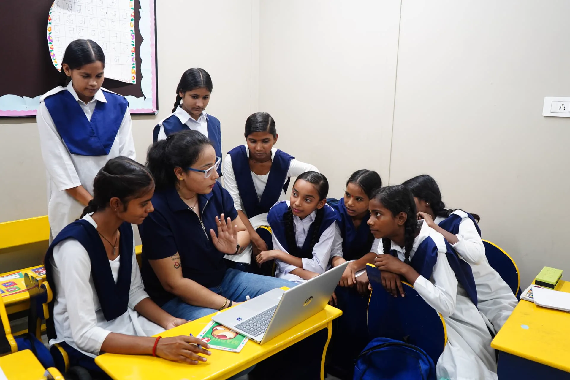 A mentor working with students around a laptop