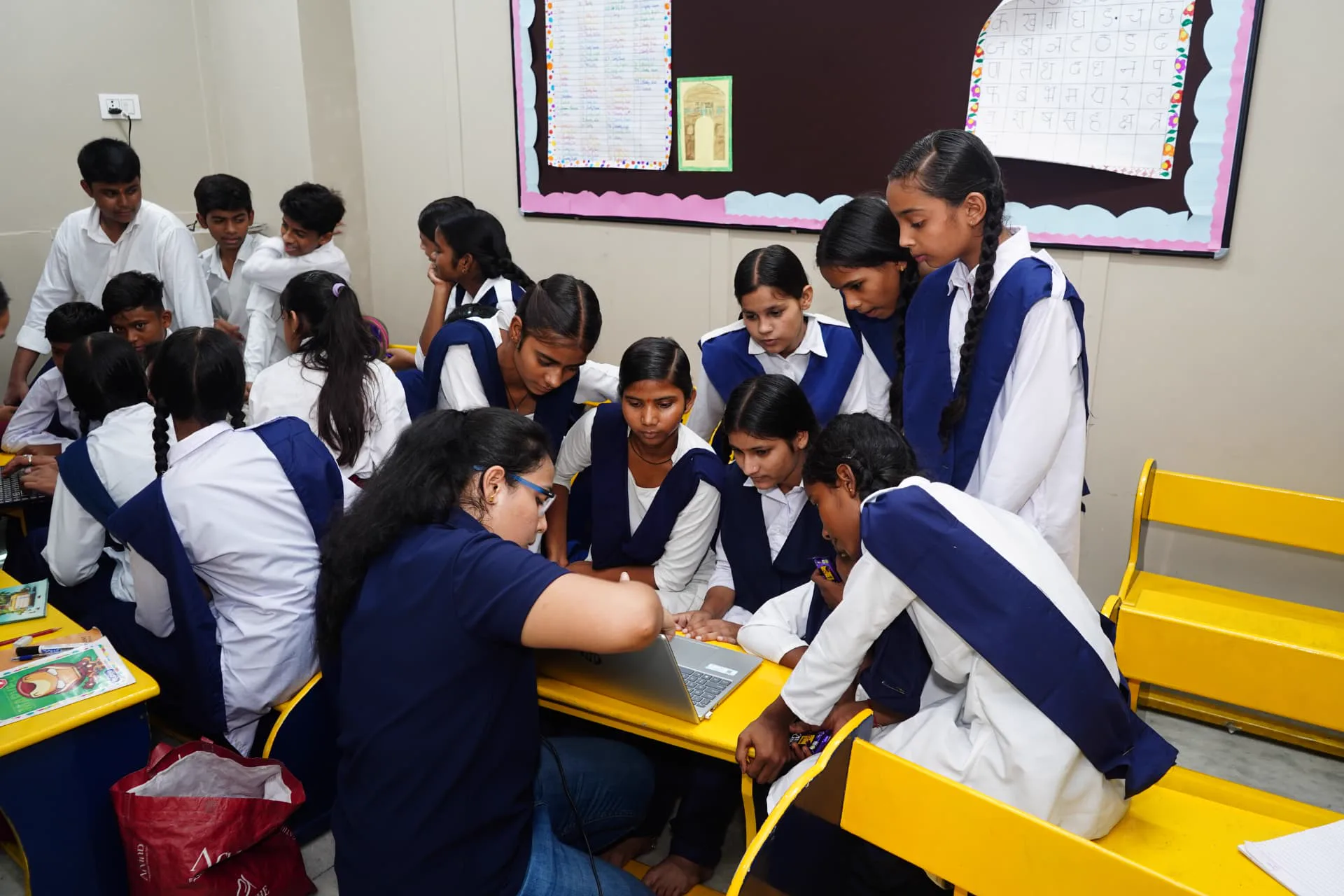 Students collaborating with a mentor using a laptop