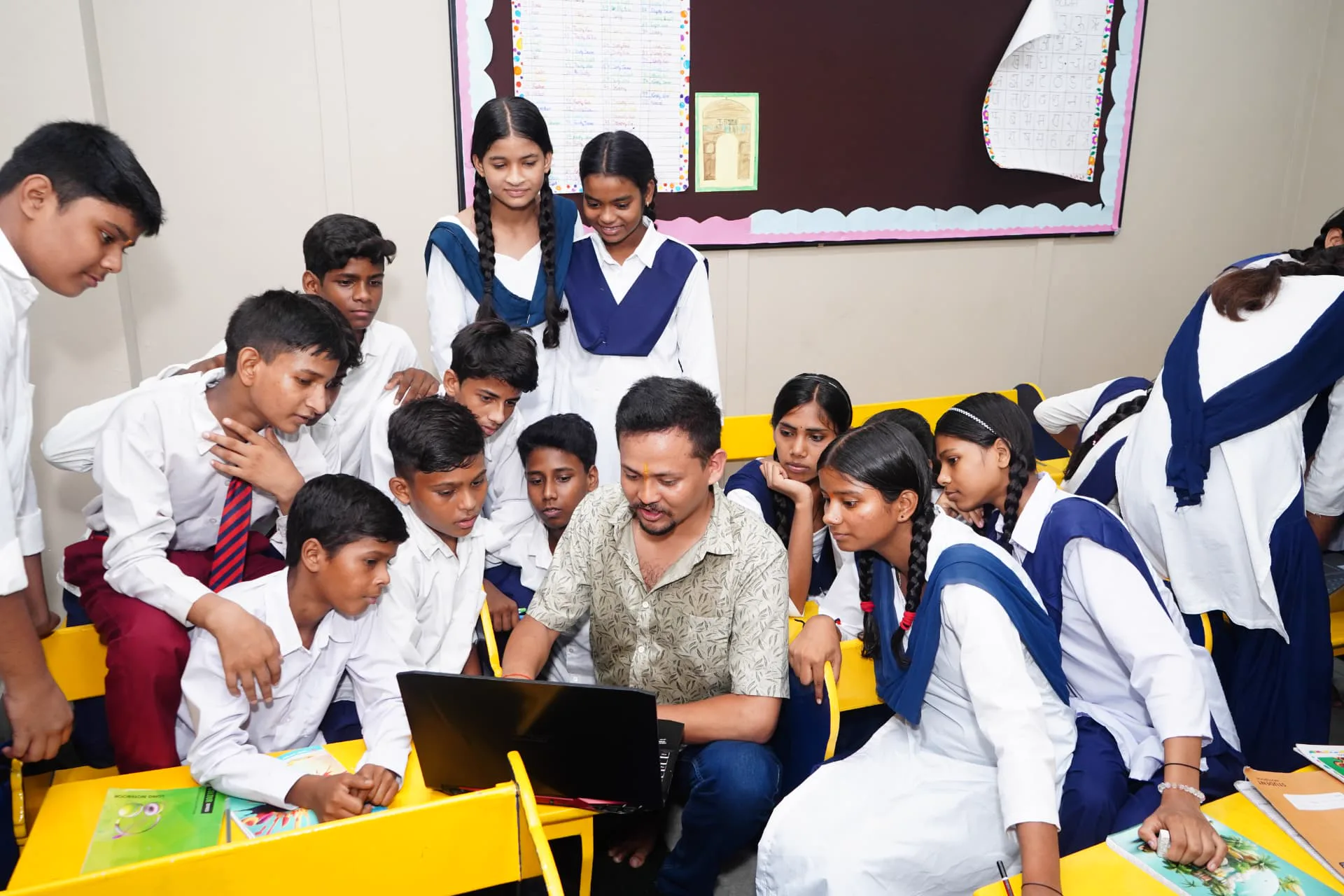 A teacher and students reviewing work on a laptop
